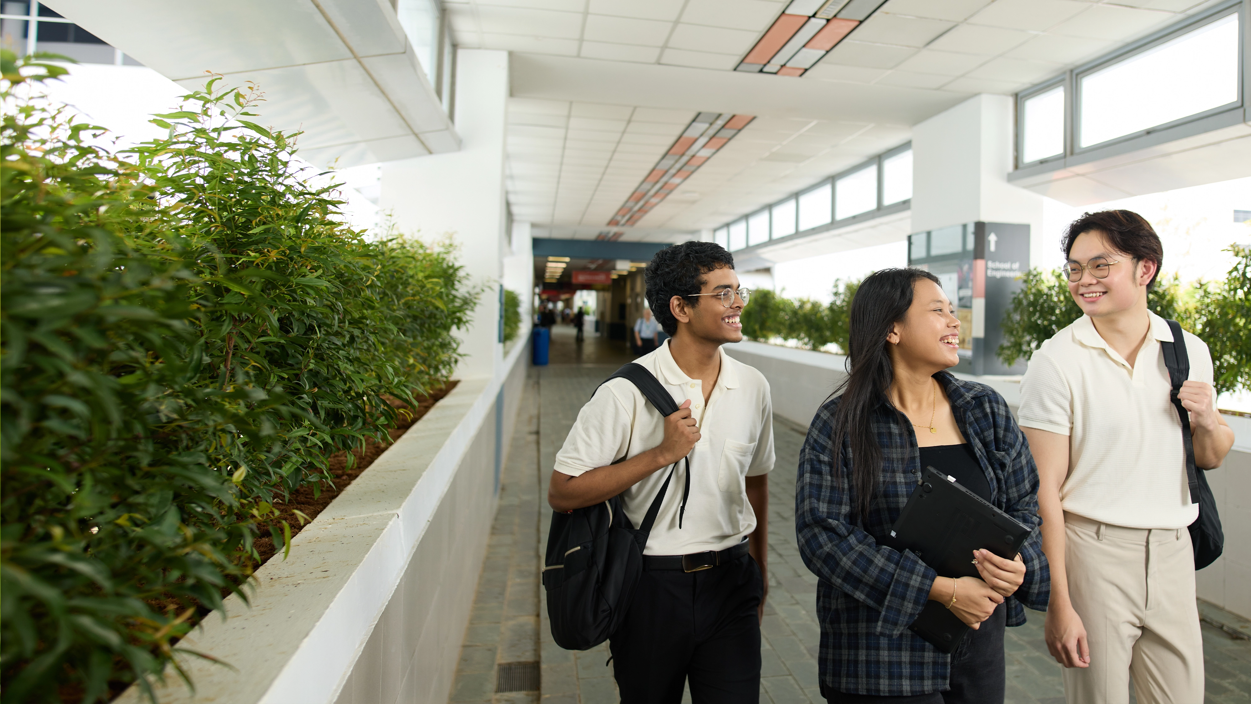 Three students walking down a corridor in the NYP campus.