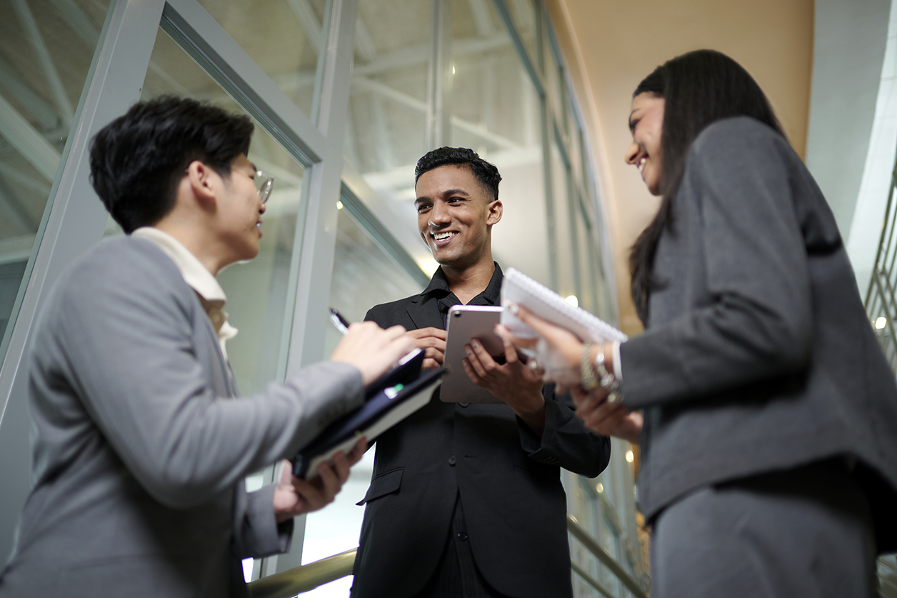 Businessman smiling as he converses with two counterparts
