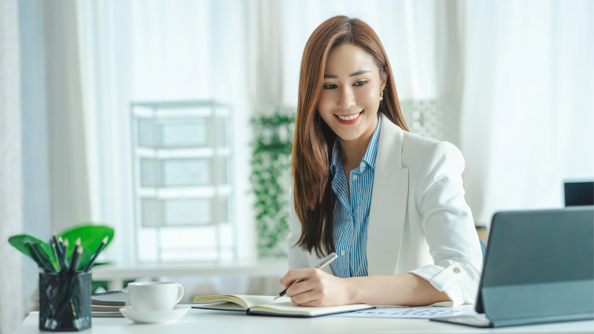 Woman in smart-formal attire looking at her iPad with a big smile