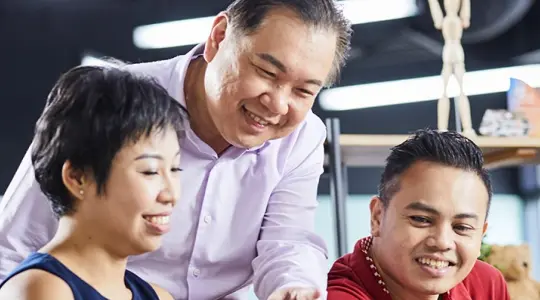 Three adults looking at laptop together