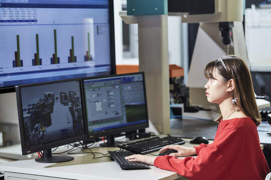 A girl looking at three desktop screens for data analysis