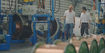 Two men in discussion as they walk down an aisle in a factory.