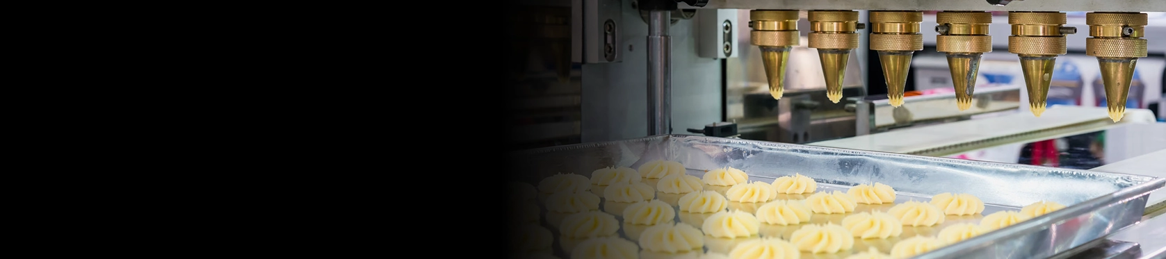 close up dough or cream and nozzle discharge of automatic biscuit or sweets making machine in production line for high technology of industrial food manufacturing