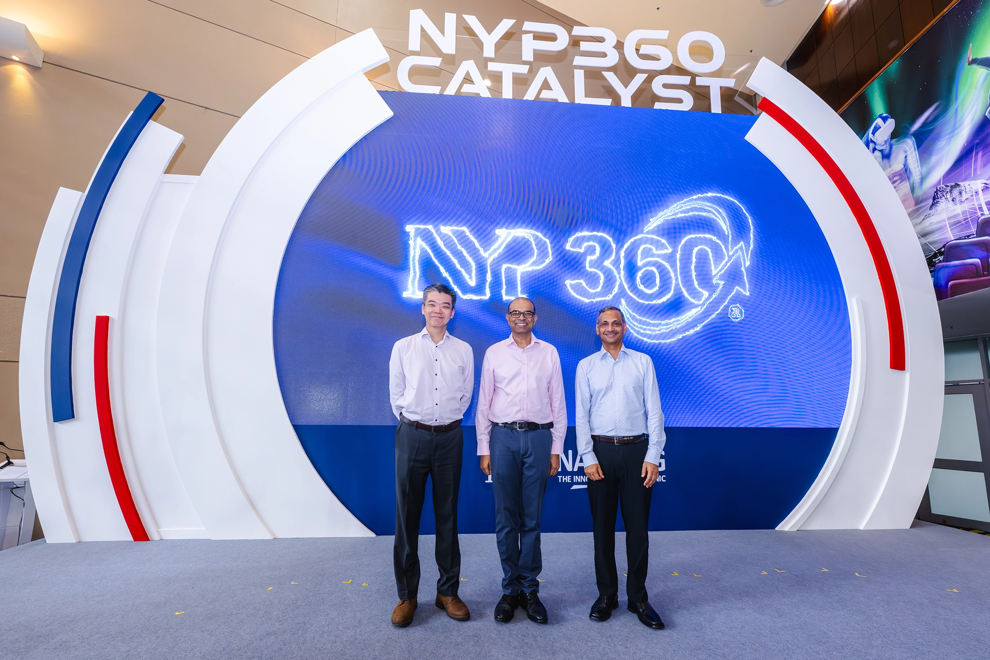 Three men standing in front of the NYP360 Catalyst event backdrop.