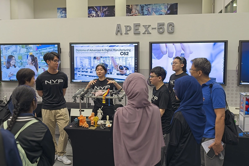 Students from the School of Engineering sharing animatedly about their project with an audience.