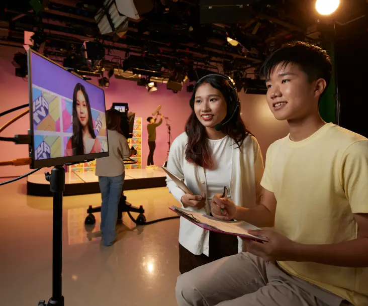 Student producer and director looking at media studio.