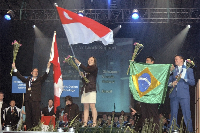 Viridis waving the Singapore flag on the top of the podium, while other award winners look at her.