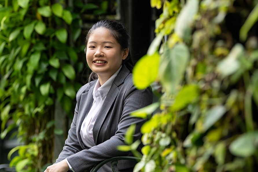 Jolene poses for a picture against greenery at NYP campus.
