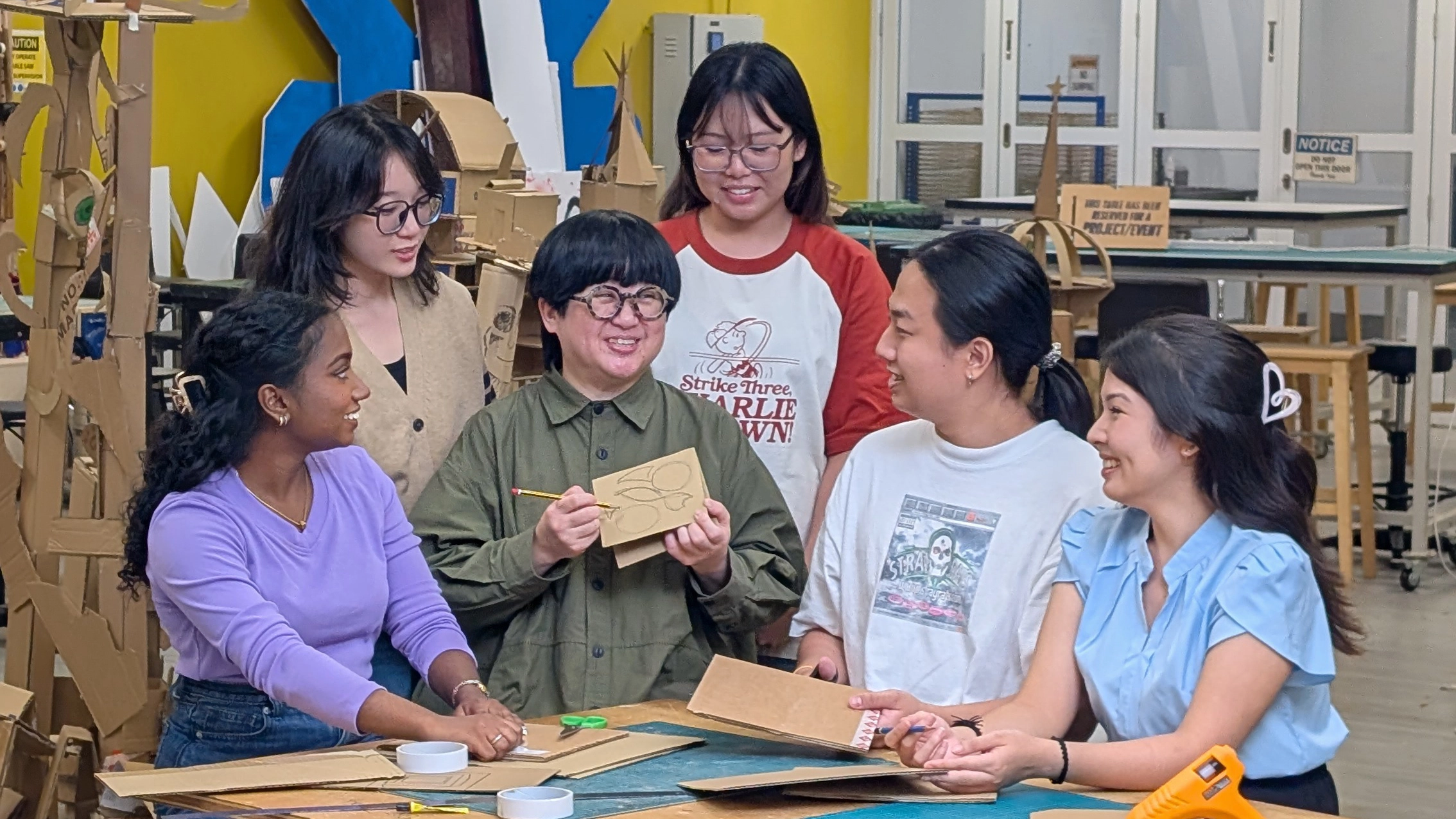 Ms Wen Lei (third from left) holding up a model to show her students surrounding her.