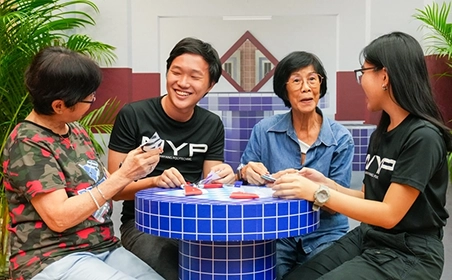 Students talking to middle-aged women at the void deck.